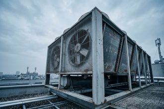 Aérocondenseur industriel installé sur le toit d'un bâtiment commercial, avec ventilateurs axiaux et ailettes en aluminium visibles