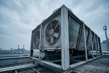 Aérocondenseur industriel installé sur le toit d'un bâtiment commercial, avec ventilateurs axiaux et ailettes en aluminium visibles