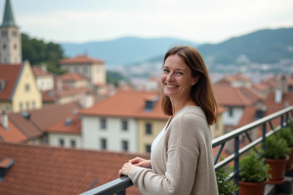 Femme souriante regardant la ville européenne depuis un balcon