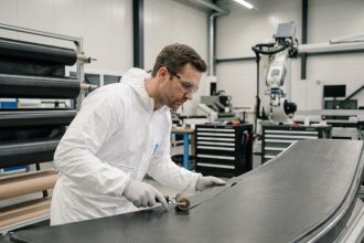 Technicien CMS France appliquant un matériau composite sur un panneau industriel dans un atelier moderne